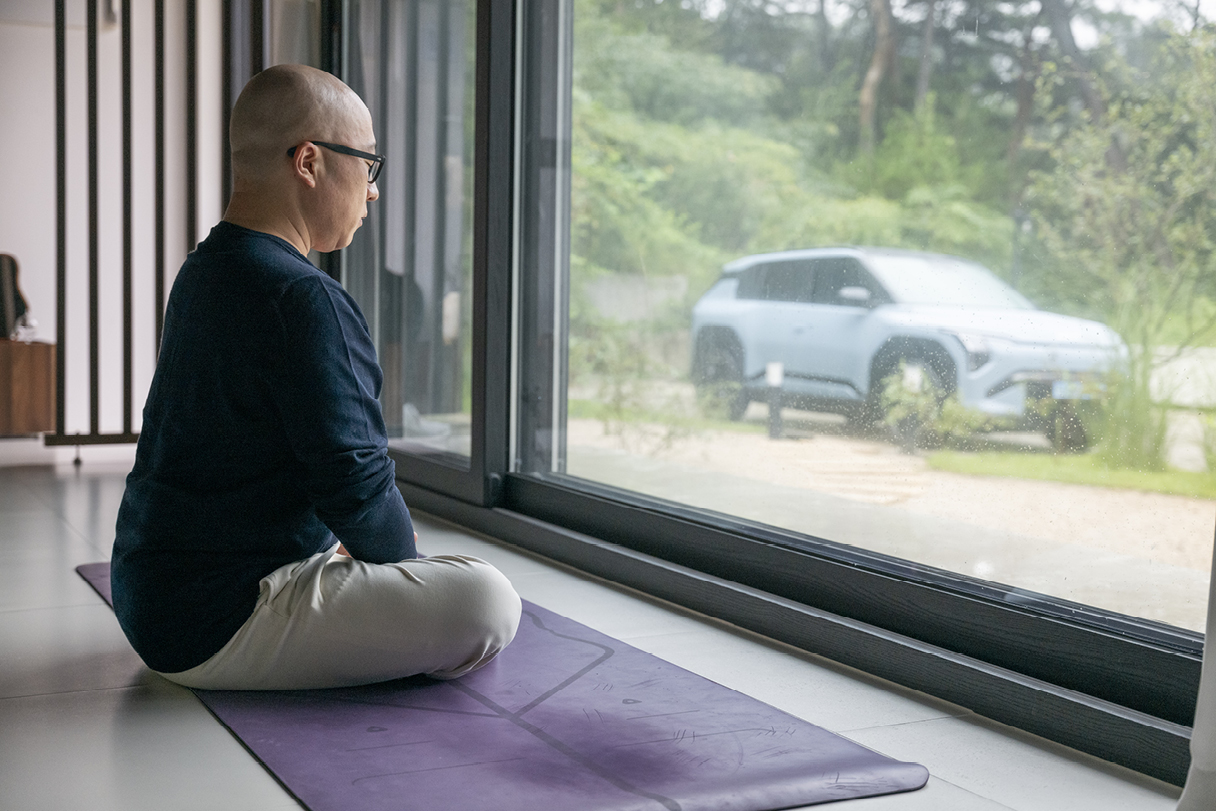 창밖으로 보이는 기아 EV3와 요가 수행 중인 정우성 칼럼니스트의 모습