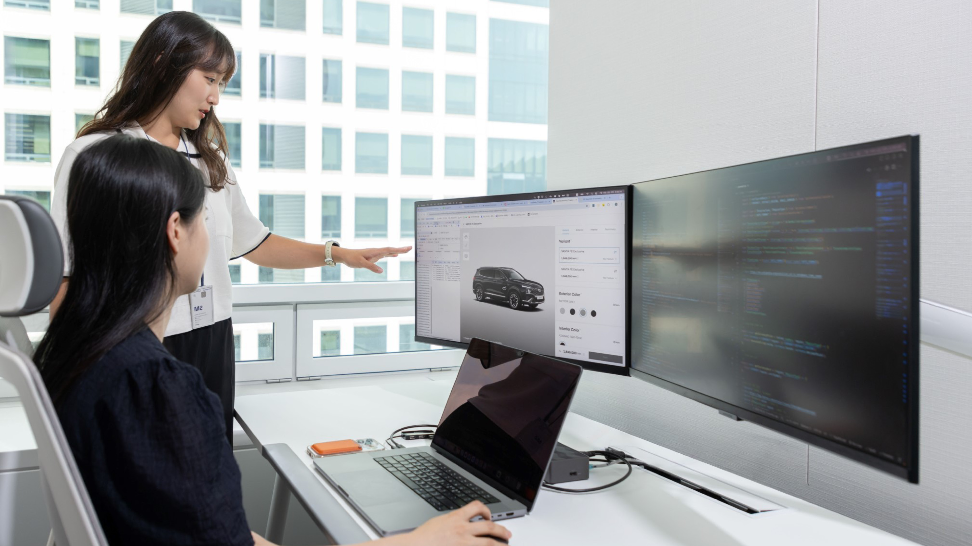 두 사람이 모니터를 보고 대화 중이다