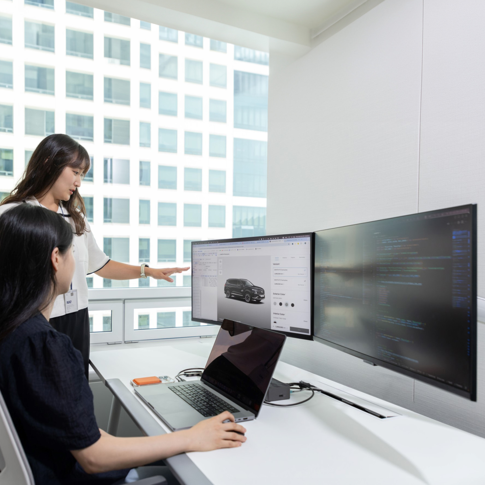 두 사람이 모니터를 보고 대화 중이다