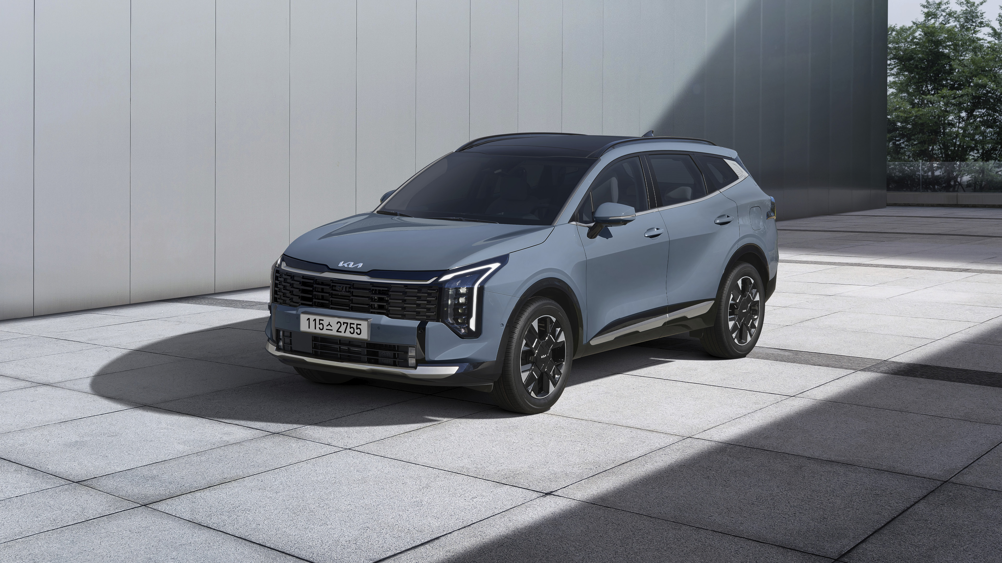 회색 건물 앞에 정차한 스포티지 전측면 모습