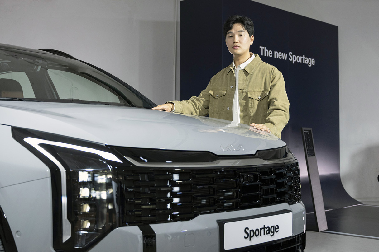 스포티지 보닛 옆에 포즈를 취한 남성