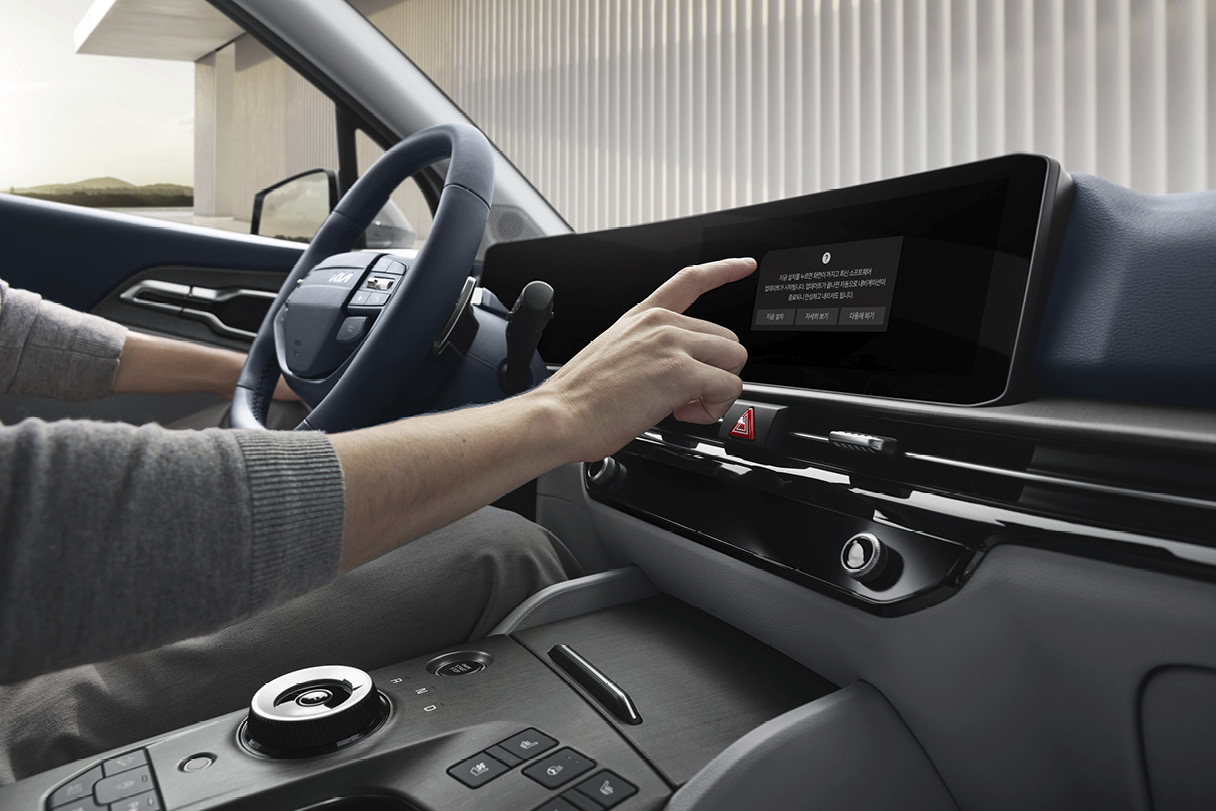 인포테인먼트를 조작하는 운전자의 손을 클로즈업한 모습