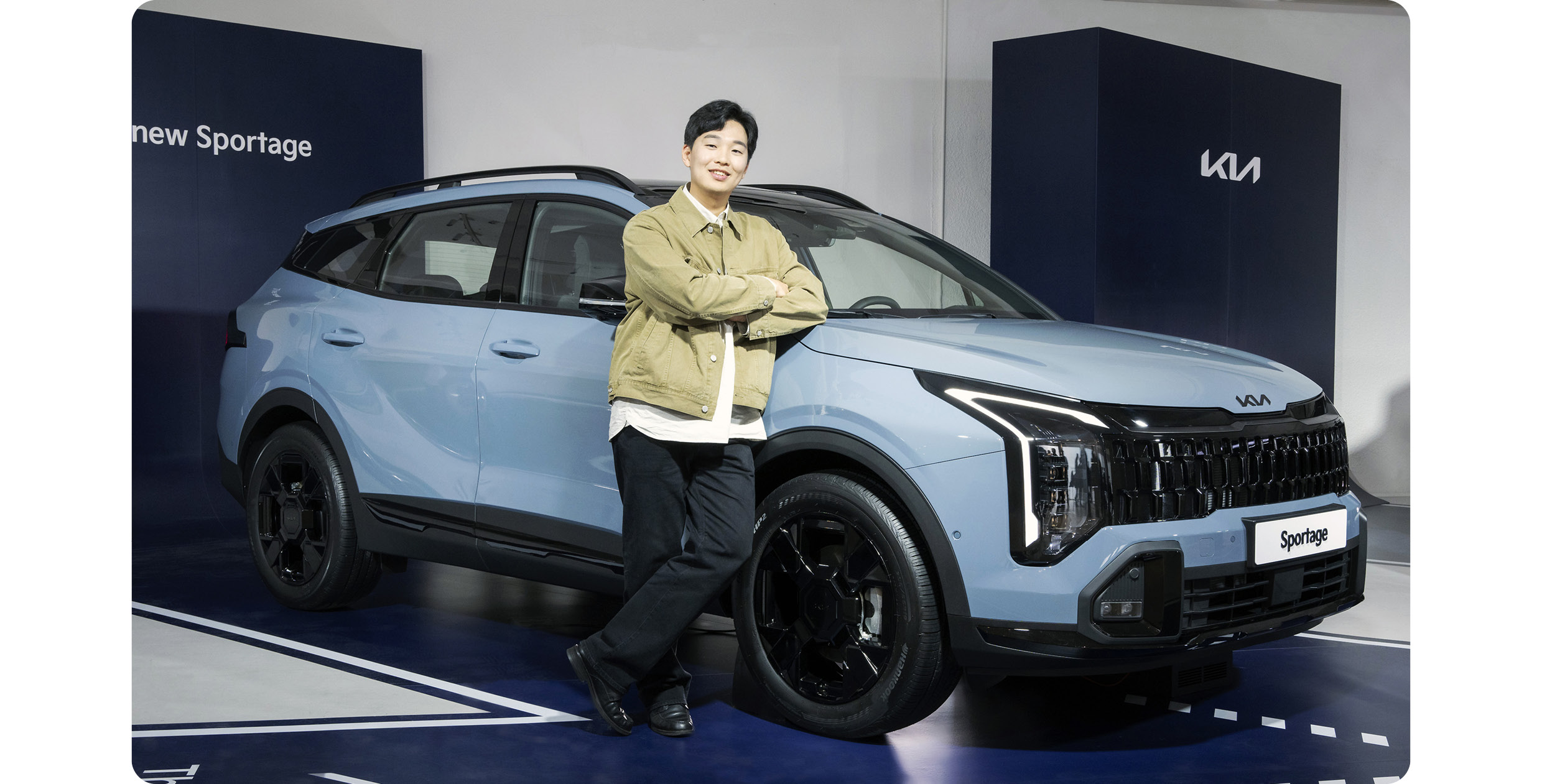 하늘색 스포티지 옆에 포즈를 취한 남성의 모습