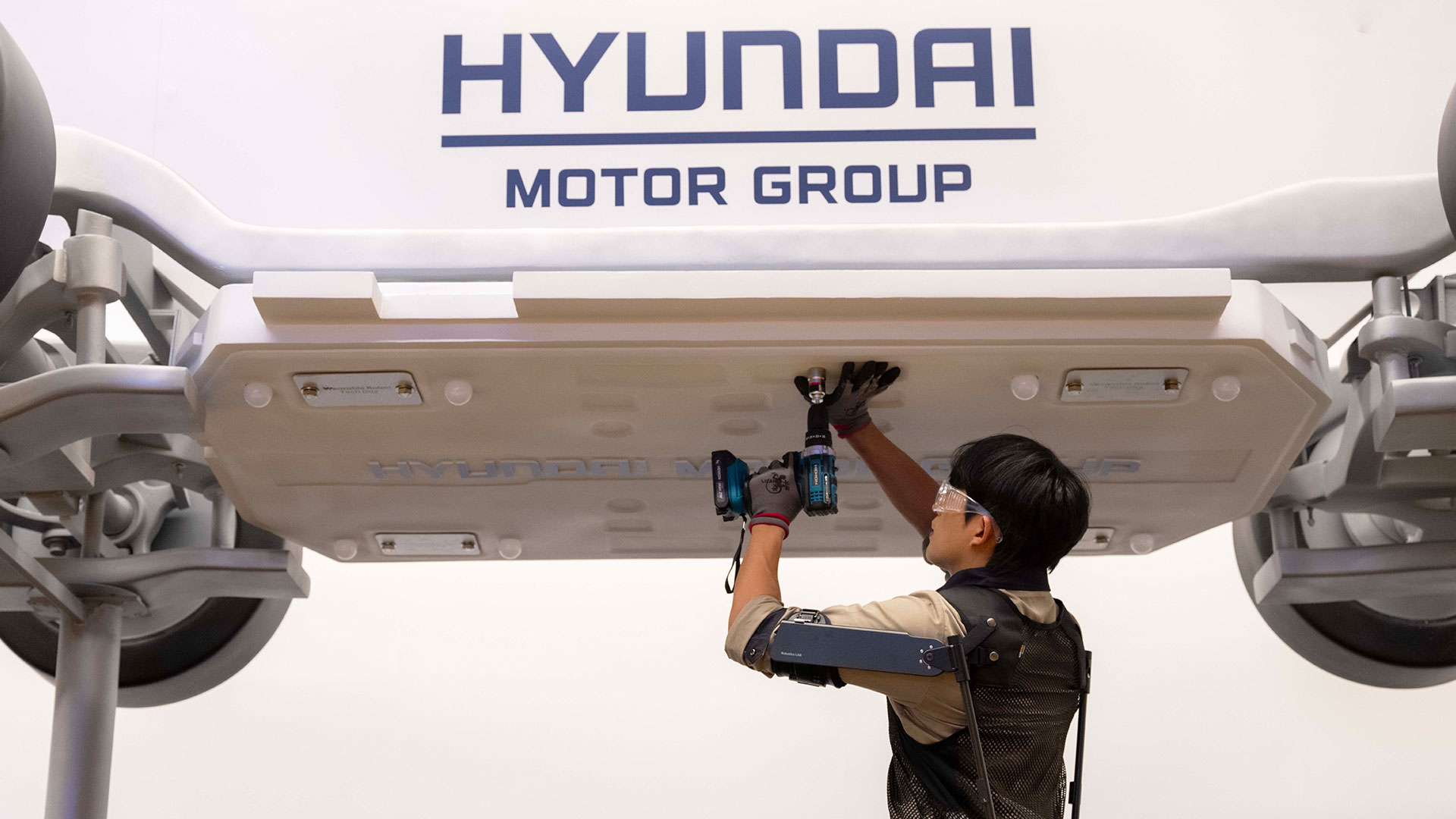 '웨어러블 로봇 테크데이'에서 상완 근력을 보조하는 '엑스블 숄더' 로봇을 착용한 로보틱스랩 연구원이 팔을 올려 모형 차량 하부의 부품을 체결하는 모습