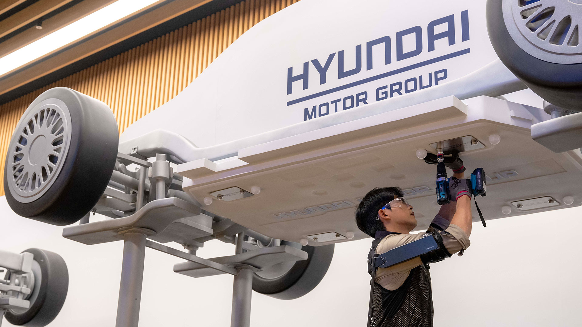 '웨어러블 로봇 테크데이'에서 상완 근력을 보조하는 '엑스블 숄더' 로봇을 착용한 로보틱스랩 연구원이 팔을 올려 모형 차량 하부의 부품을 체결하는 모습