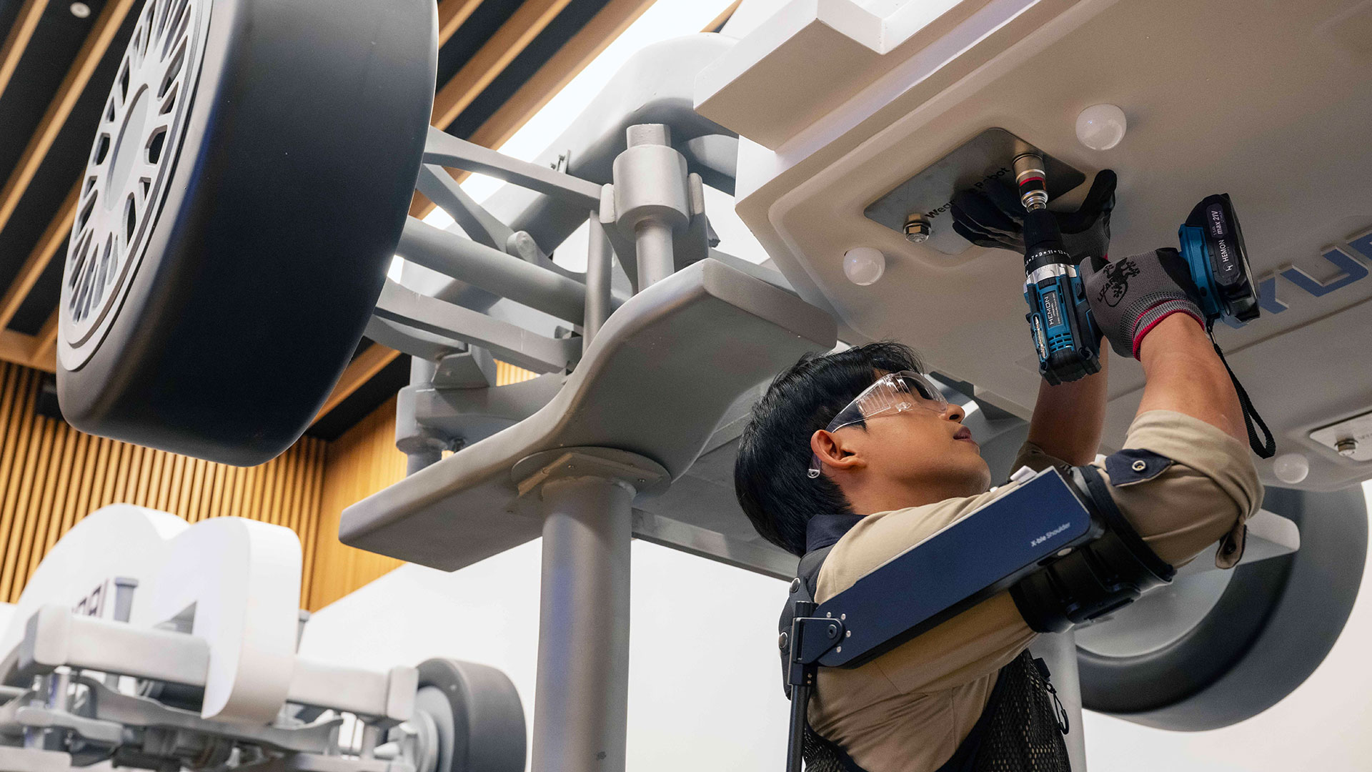 '웨어러블 로봇 테크데이'에서 상완 근력을 보조하는 '엑스블 숄더' 로봇을 착용한 로보틱스랩 연구원이 팔을 올려 모형 차량 하부의 부품을 체결하는 모습