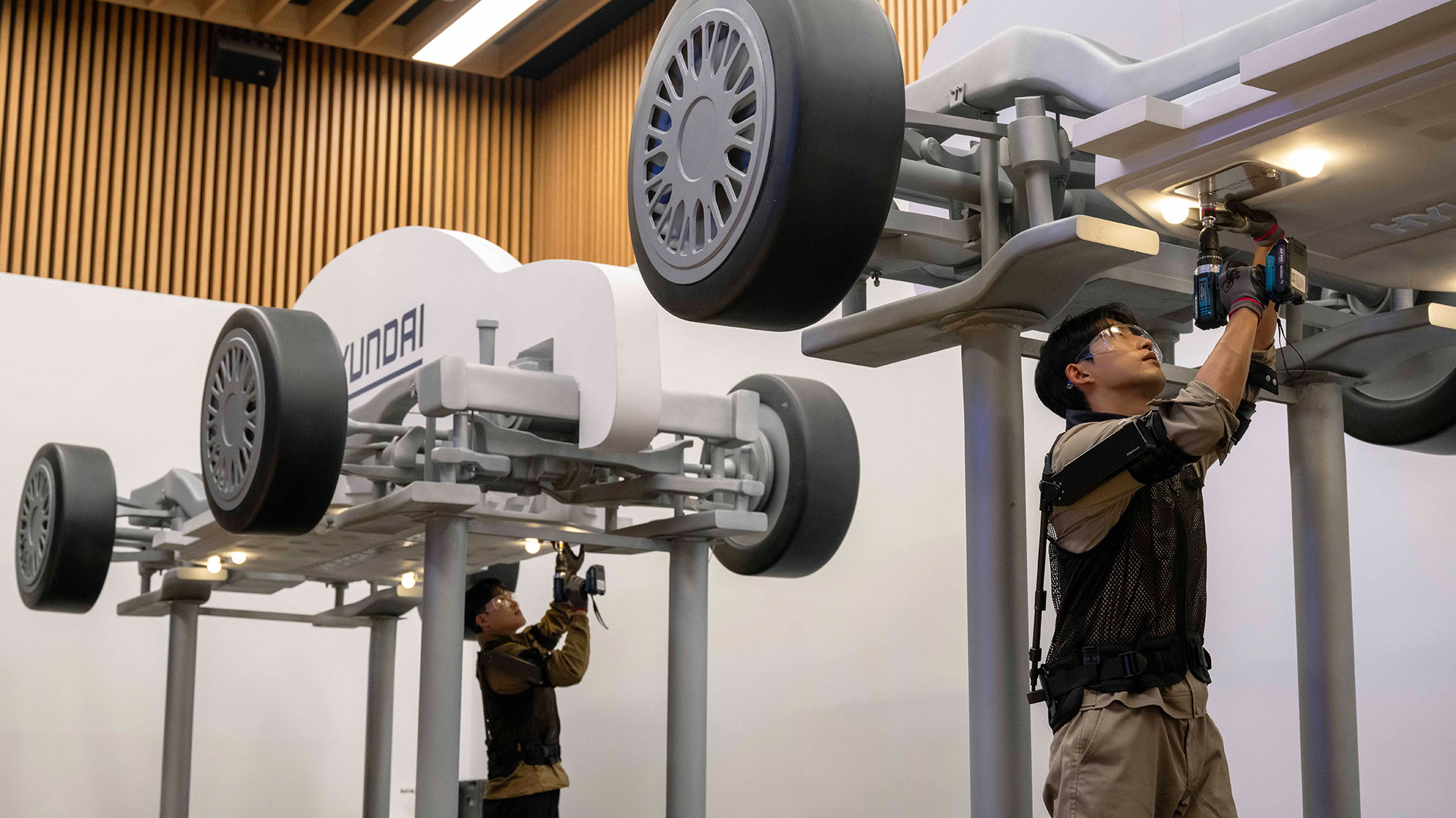 '웨어러블 로봇 테크데이'에서 상완 근력을 보조하는 '엑스블 숄더' 로봇을 착용한 로보틱스랩 연구원이 팔을 올려 모형 차량 하부의 부품을 체결하는 모습