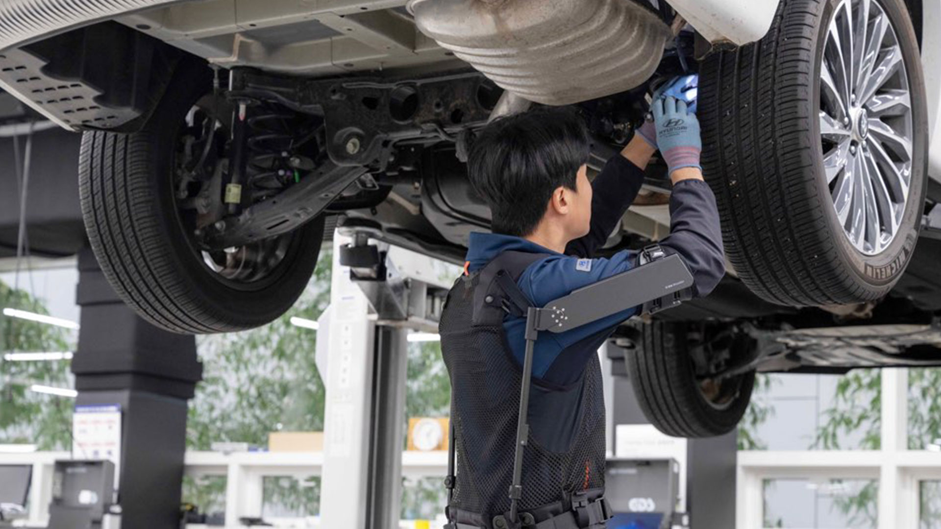 현대자동차 고양하이테크센터에서 작업자가 ‘엑스블 숄더’를 착용하고 차량 하부를 정비하는 모습