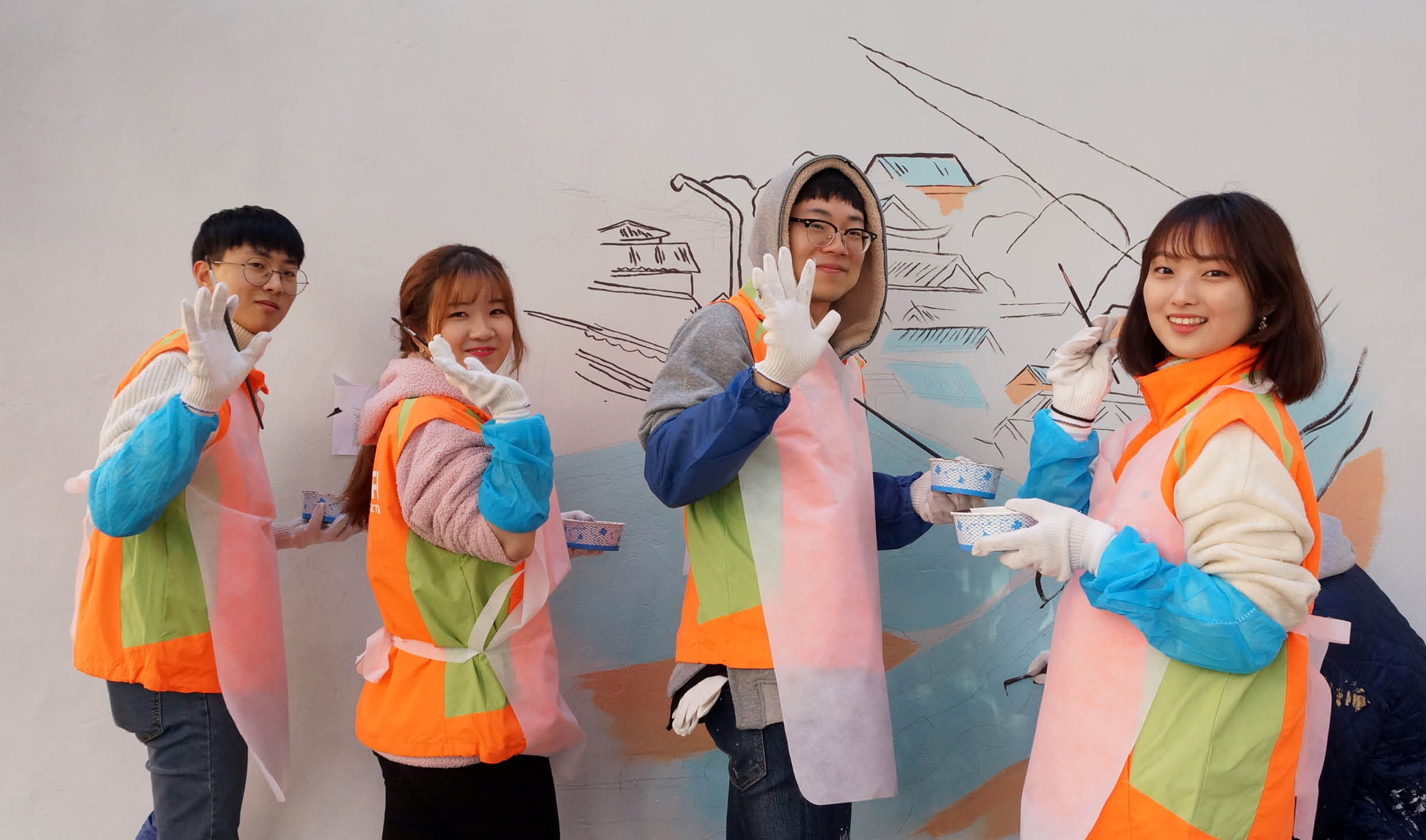 여러 명의 성인이 벽화를 그리는 모습