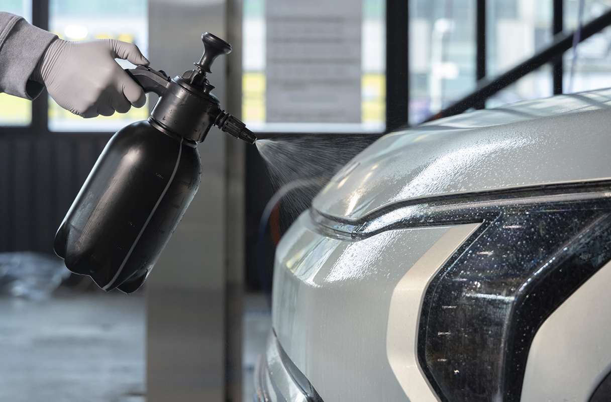 spraying detergent on the exterior of a car