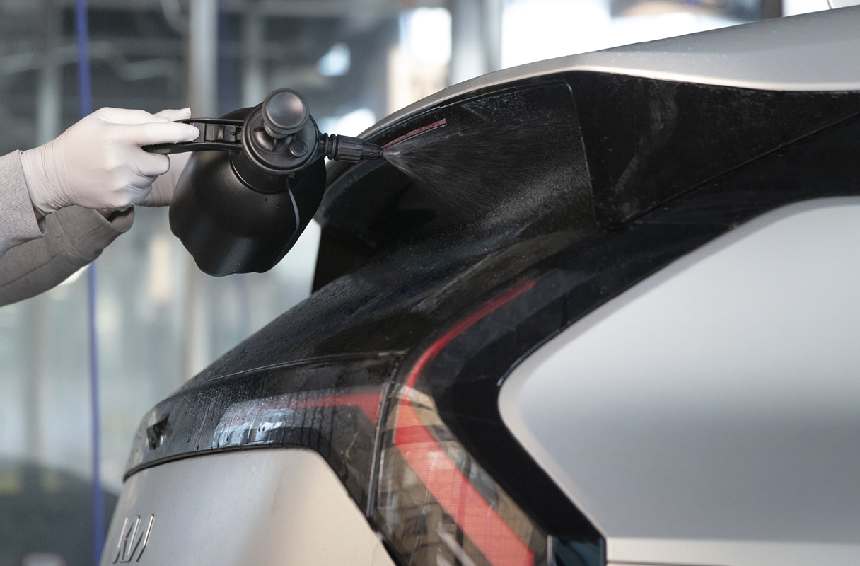 spraying detergent on the exterior of a car