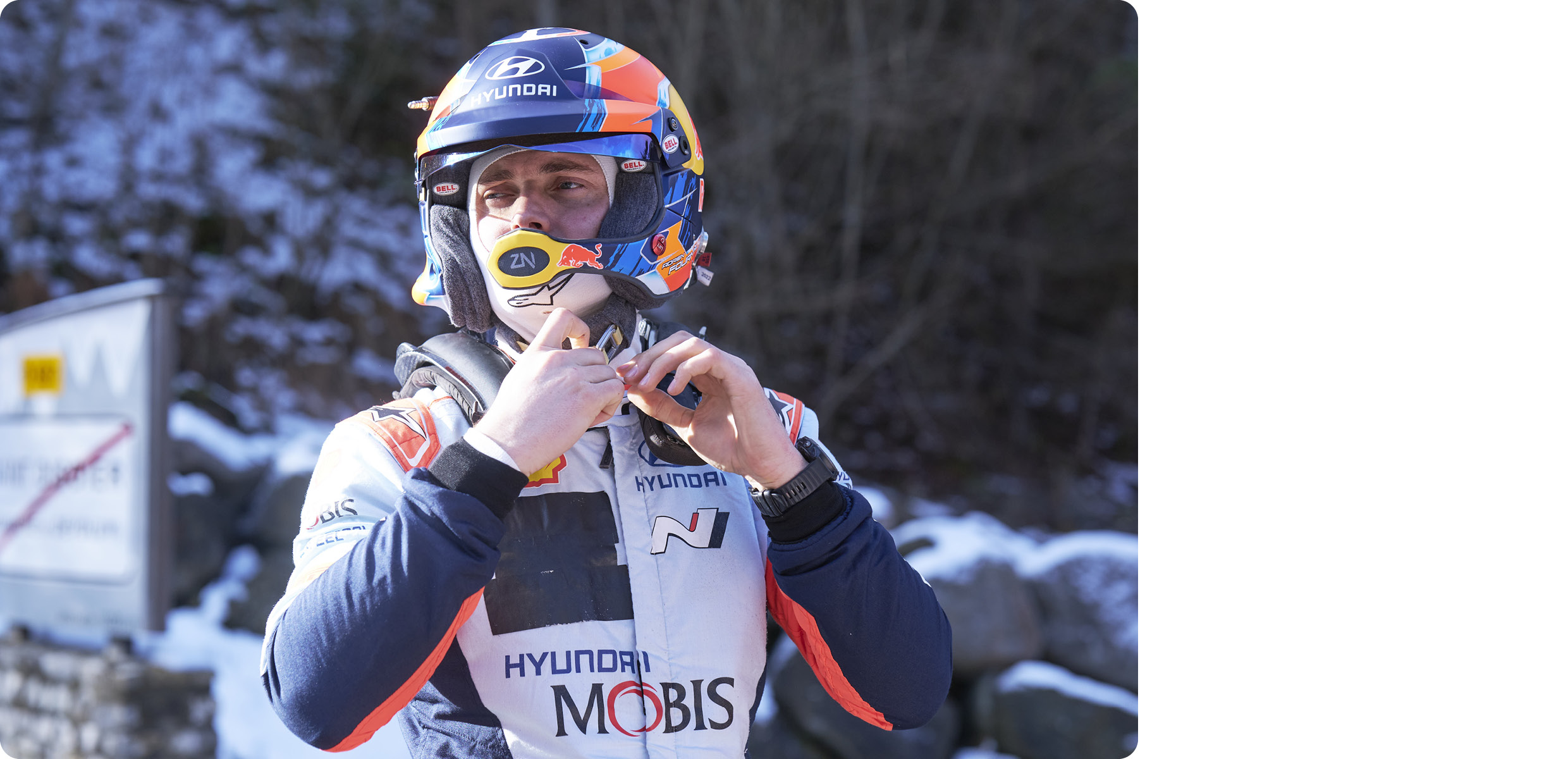 The Hyundai team driver is tightening the helmet's chin strap