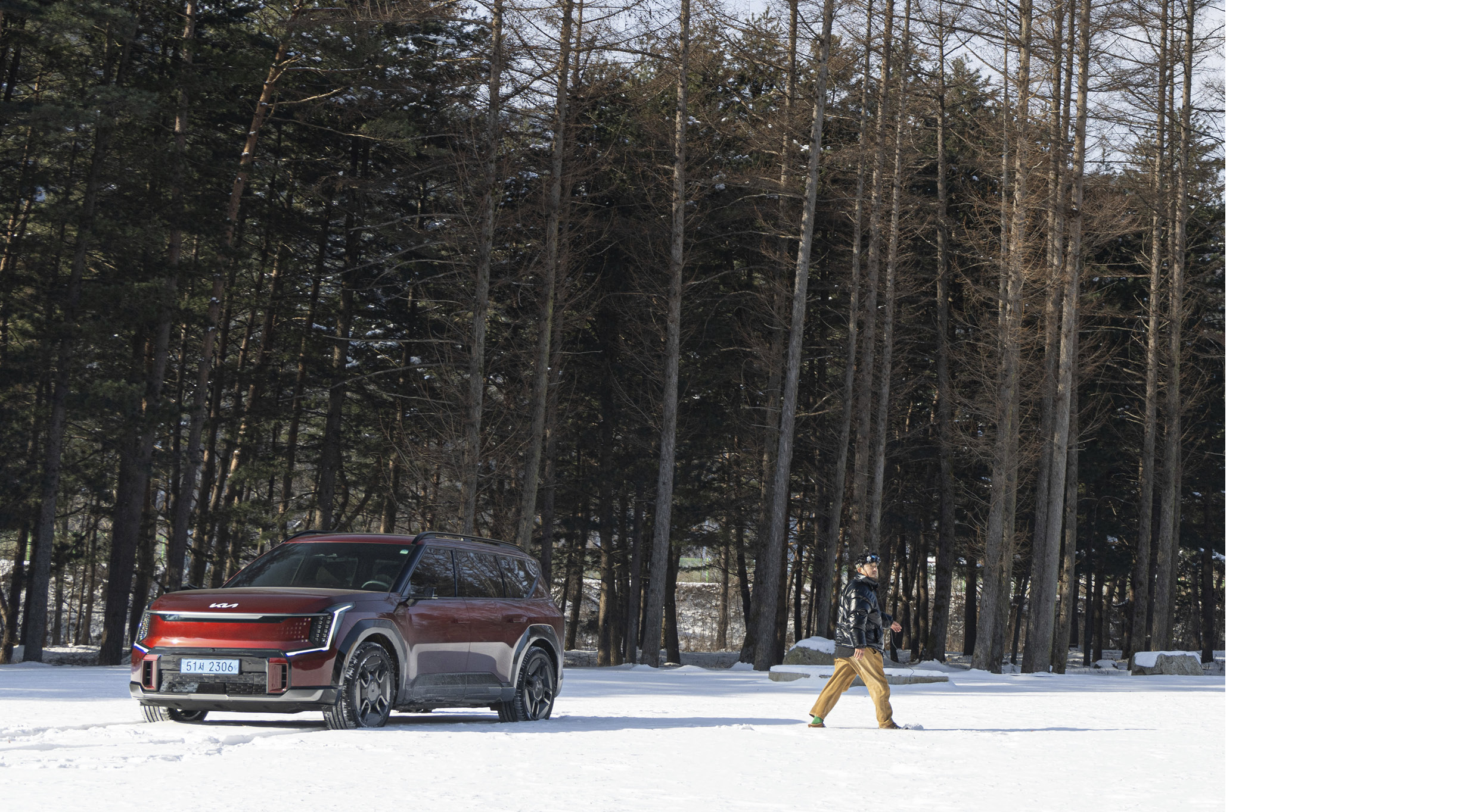 눈 위에 있는 기아 EV9과 드론 촬영 감독의 모습
