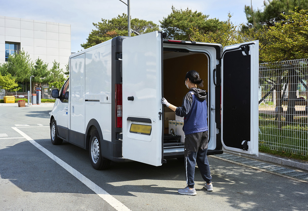 택배 기사가 ST1의 적재함에 다가가는 모습
