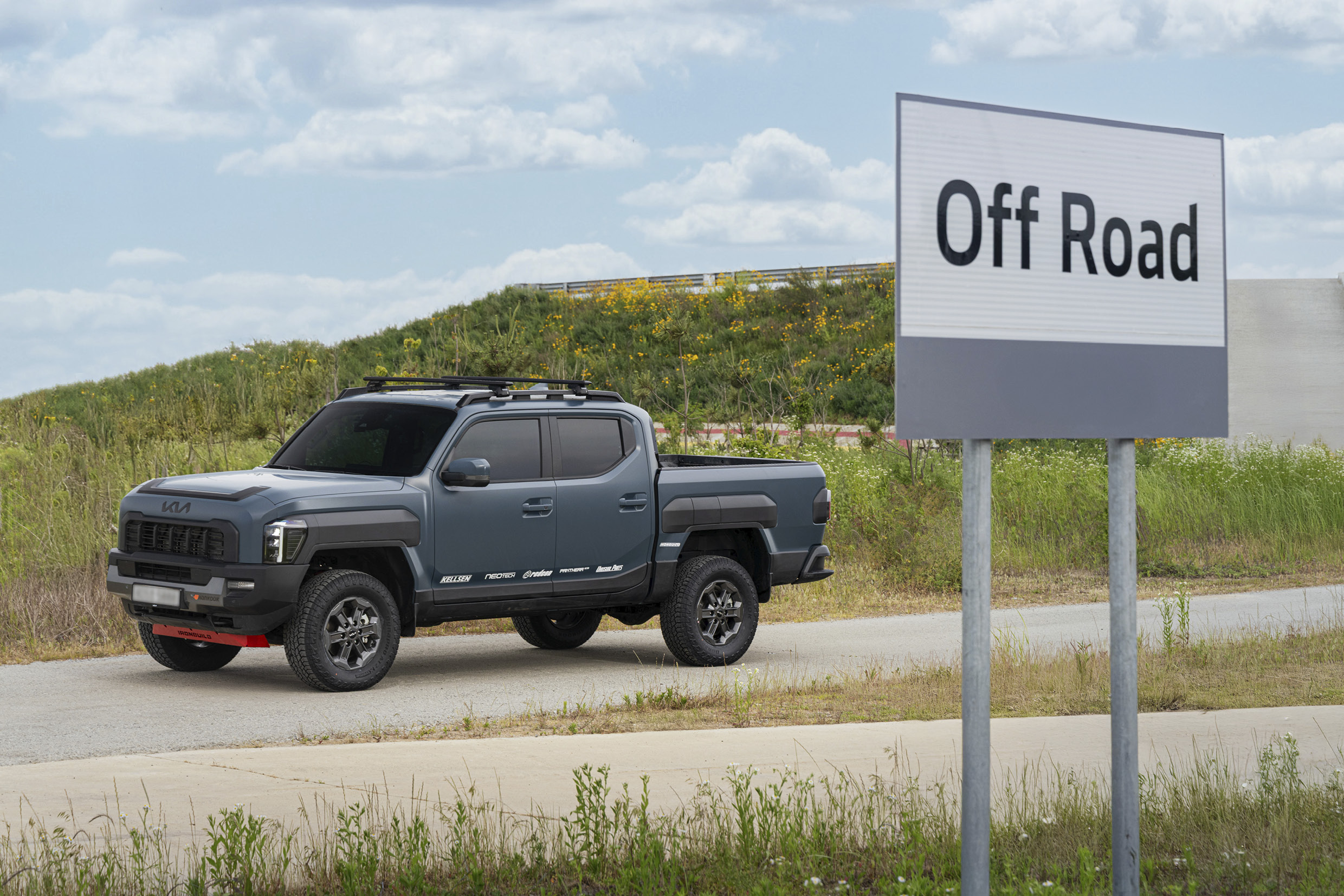 기아 타스만 오프로드 코스 위에 서 있는 모습