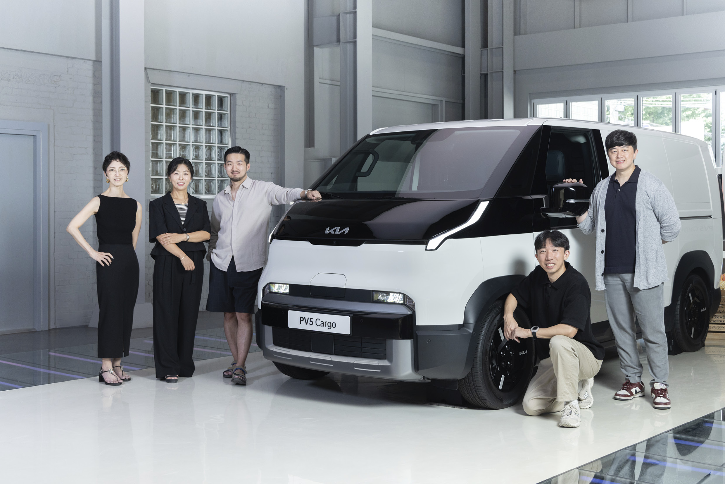 기아 PV5와 함께 서 있는 디자이너들의 모습