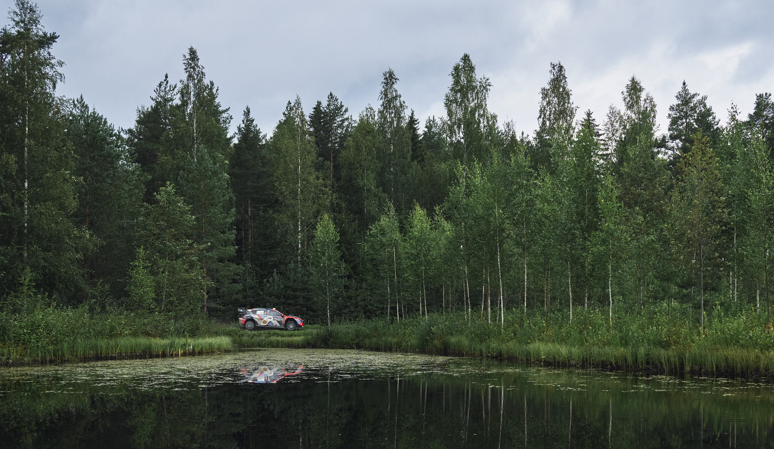 Rally car driving along a lake