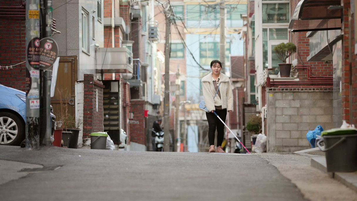 골목길을 걷고 있는 시각장애인의 모습