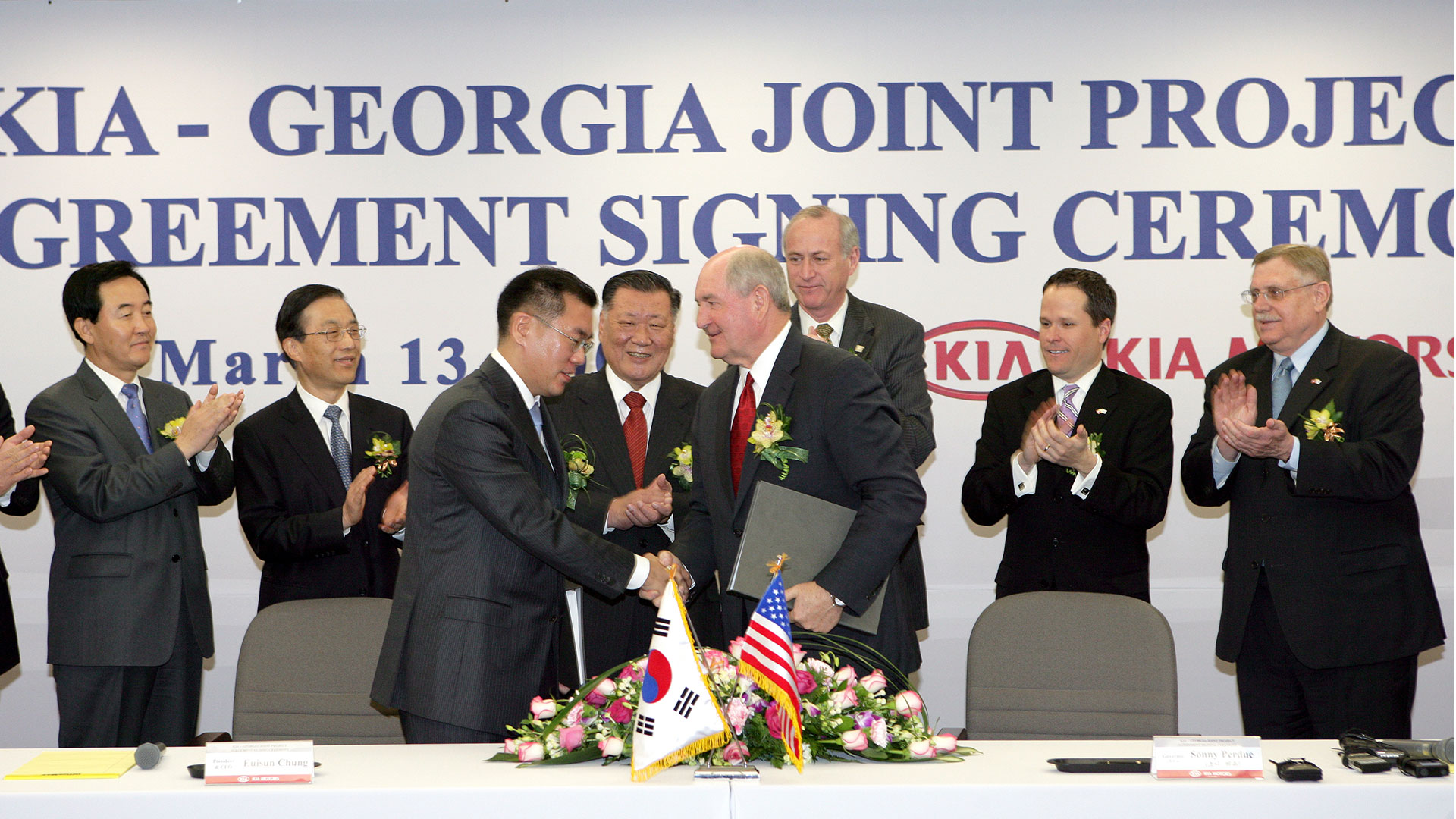 2006년 기아 조지아공장 투자계약식에서 정몽구 명예회장이 지켜보는 가운데 정의선 회장과 소니 퍼듀 조지아 주지사가 투자 계약서에 서명한 후 악수하고 있다.