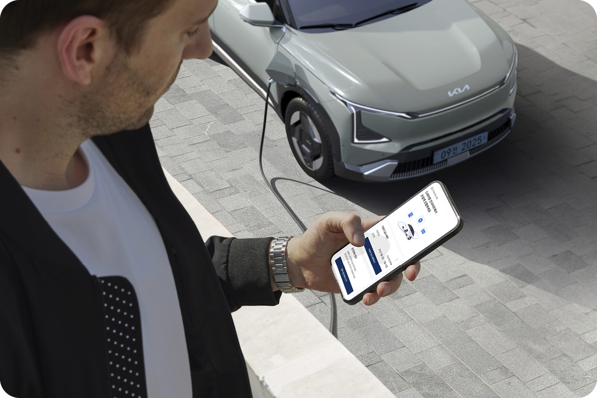 전기차를 충전하며 스마트폰으로 차량을 관리하는 모습