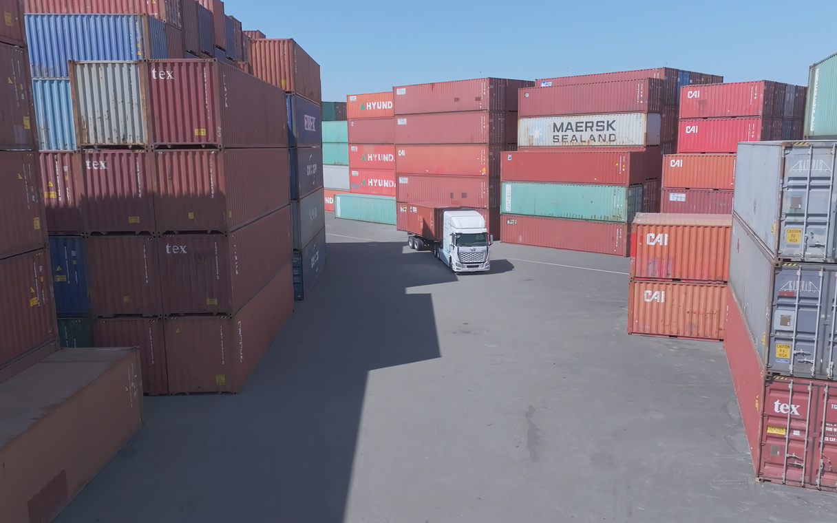 엑시언트 수소전기트럭이 컨테이너 더미 사이에 있는 모습