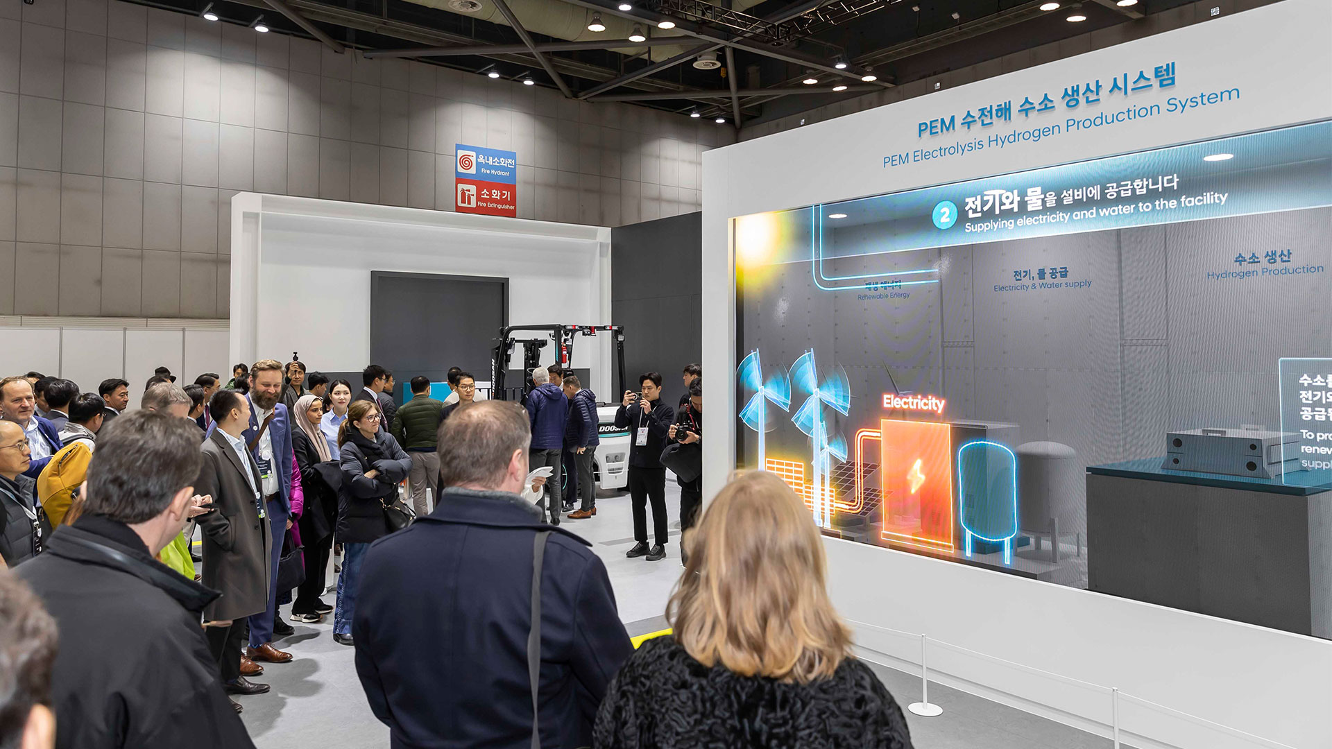 관람객들이 PEM 수전해 수소 생산 시스템 관련 전시물을 둘러보고 있는 모습
