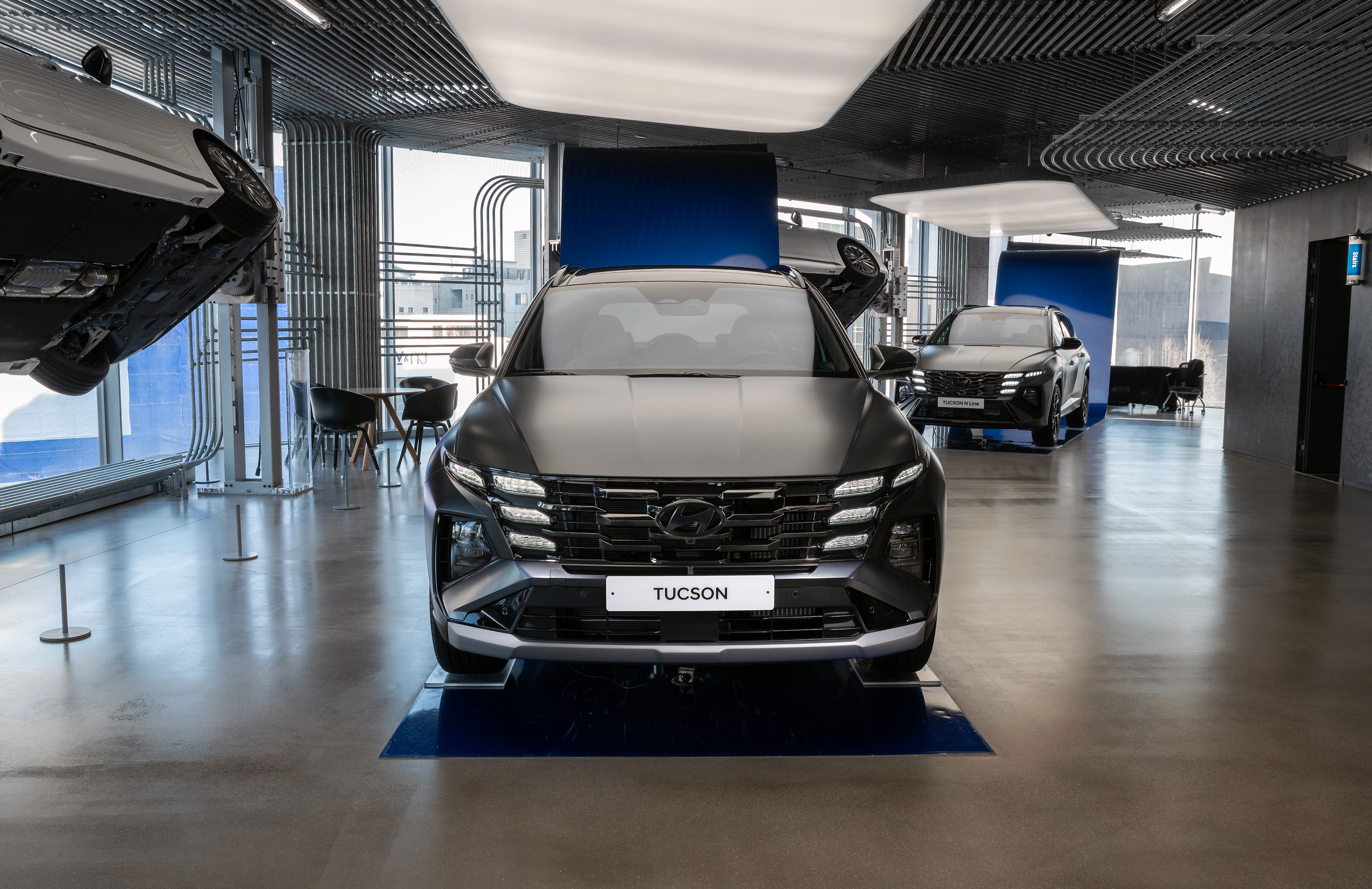 현대모터스튜디오 실내 공간에 전시된 현대자동차 투싼 차량의 정면.