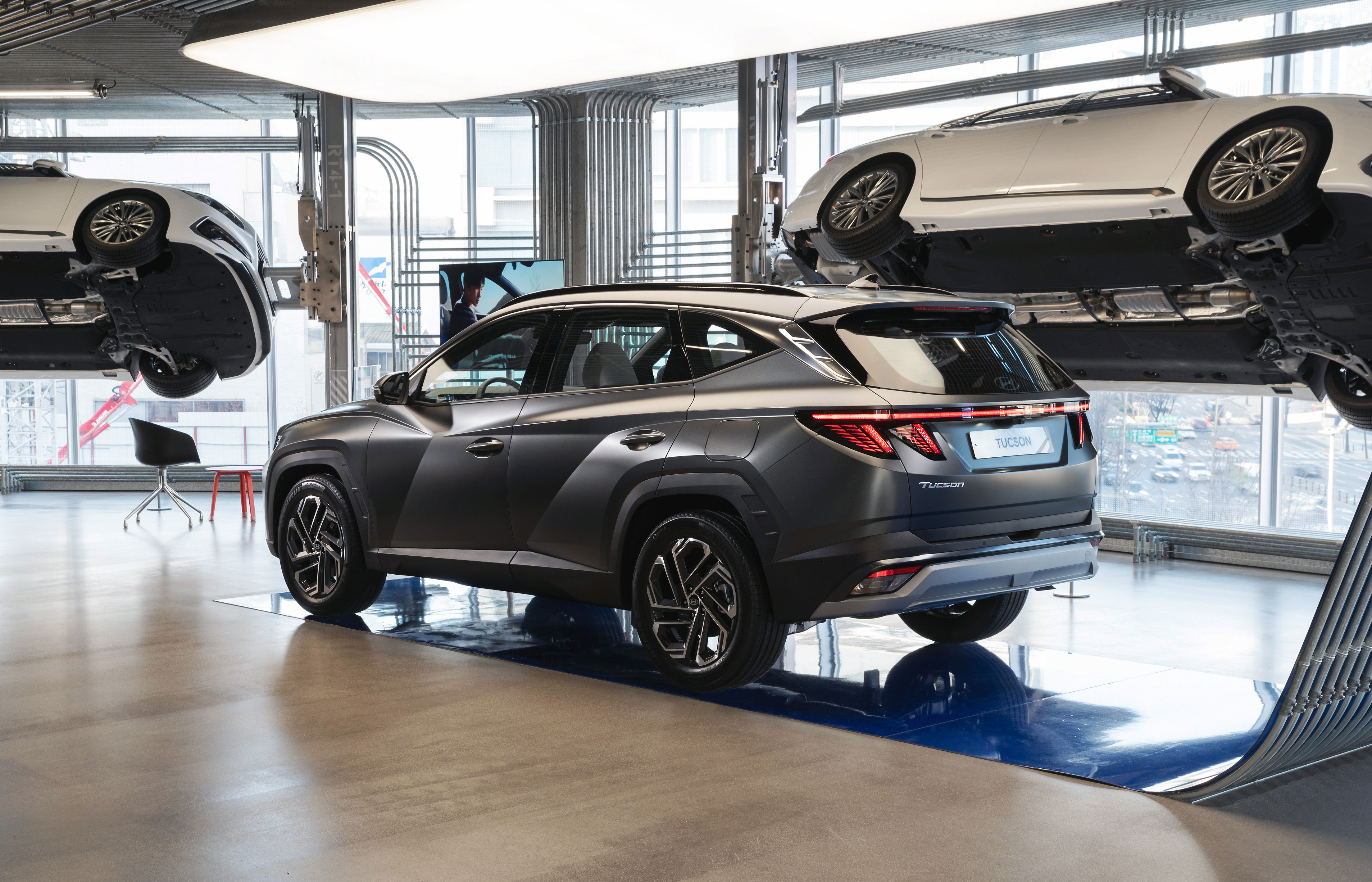 현대모터스튜디오 실내 전시장에서 투싼 SUV 측후면과 리프트에 올려진 차량 하부가 함께 전시.