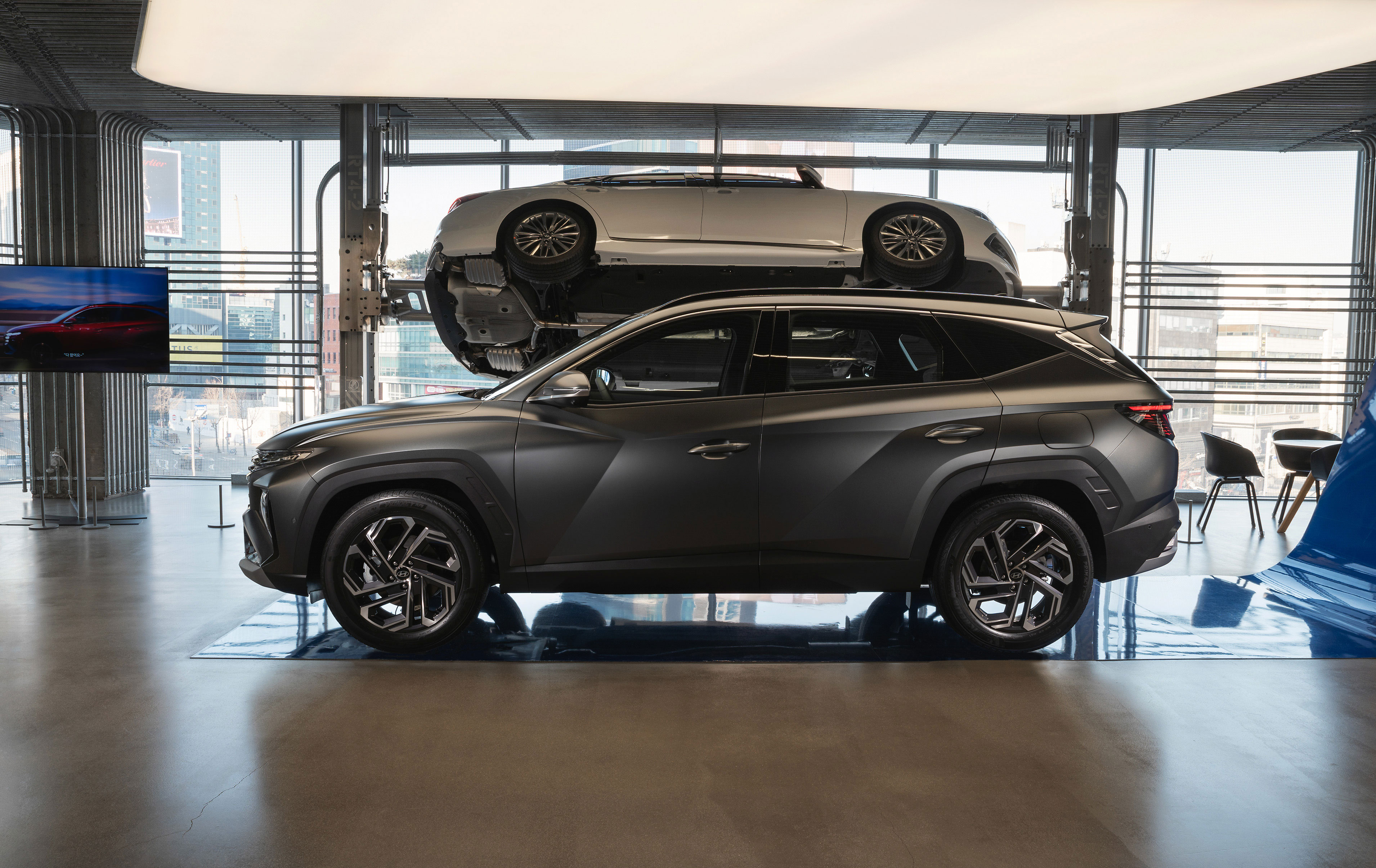 현대모터스튜디오 실내 전시장에 투싼 차량 측면과 리프트에 올려진 차량 하부가 함께 전시.