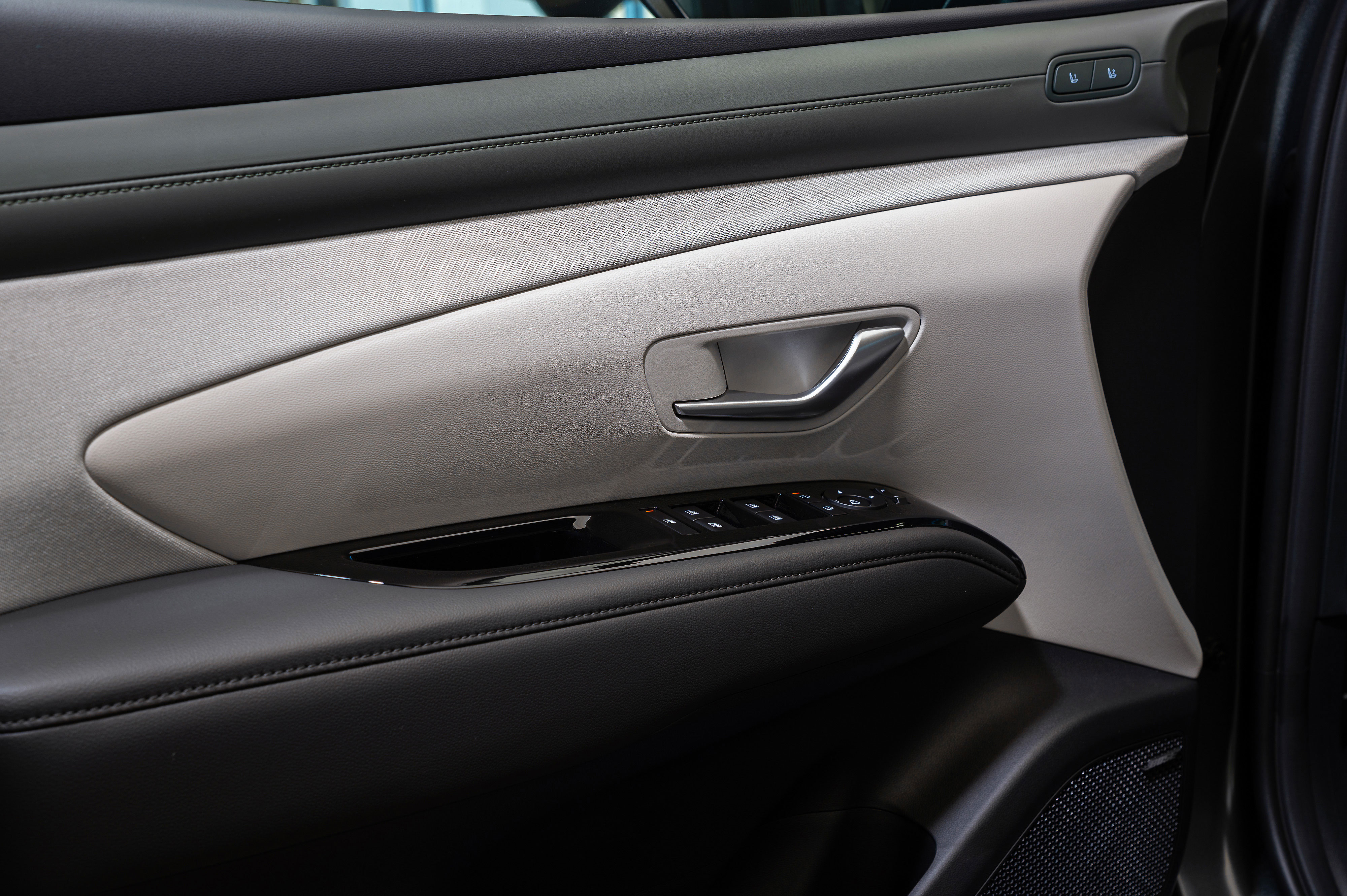 투싼 차량 내장 도어 트림의 손잡이와 창문 조작 버튼.