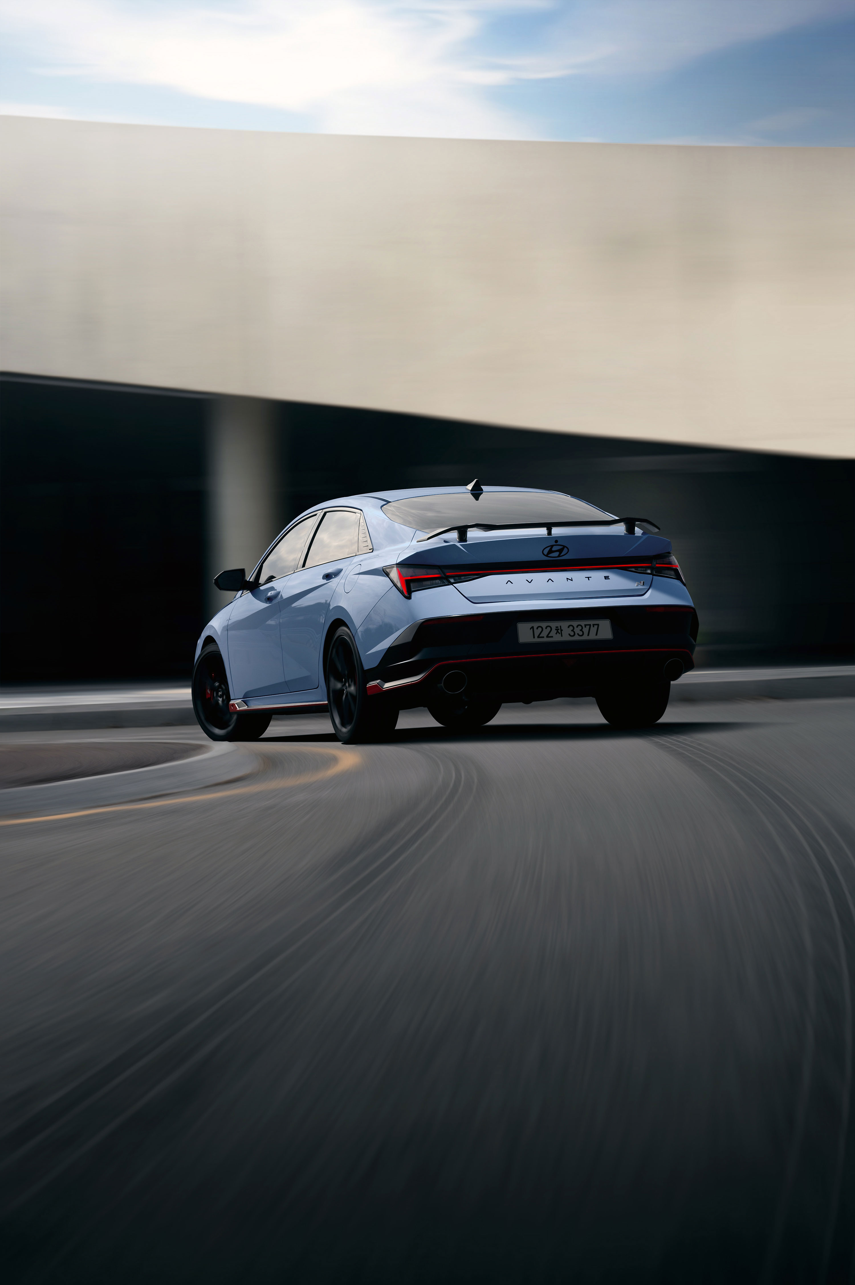 곡선 도로 위에서 주행중인 하늘색 더 뉴 아반떼 N 차량의 후면