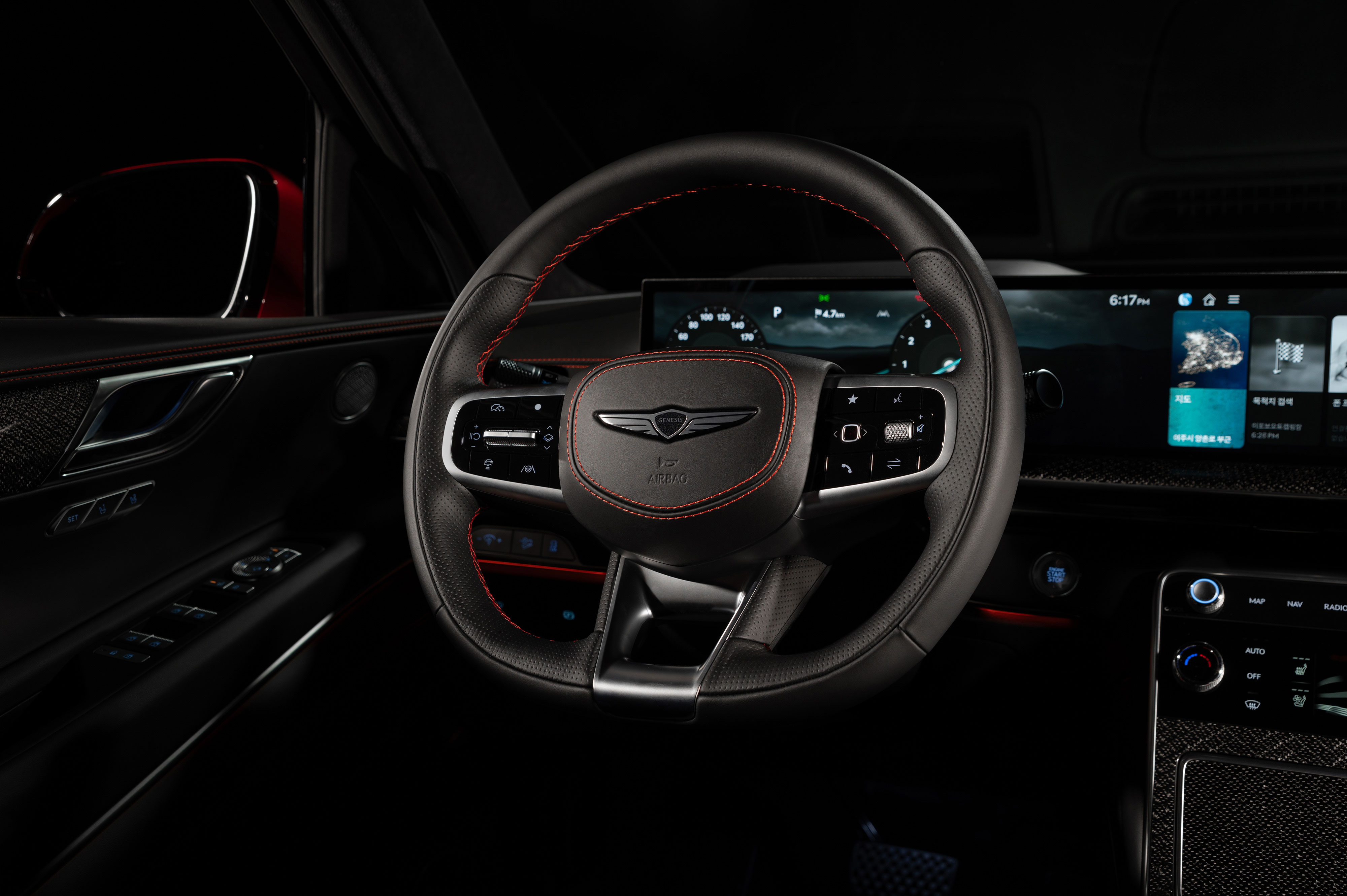 어두운 실내에서 제네시스 GV80 쿠페의 스티어링 휠과 디지털 계기판, 인포테인먼트 화면 부분 확대