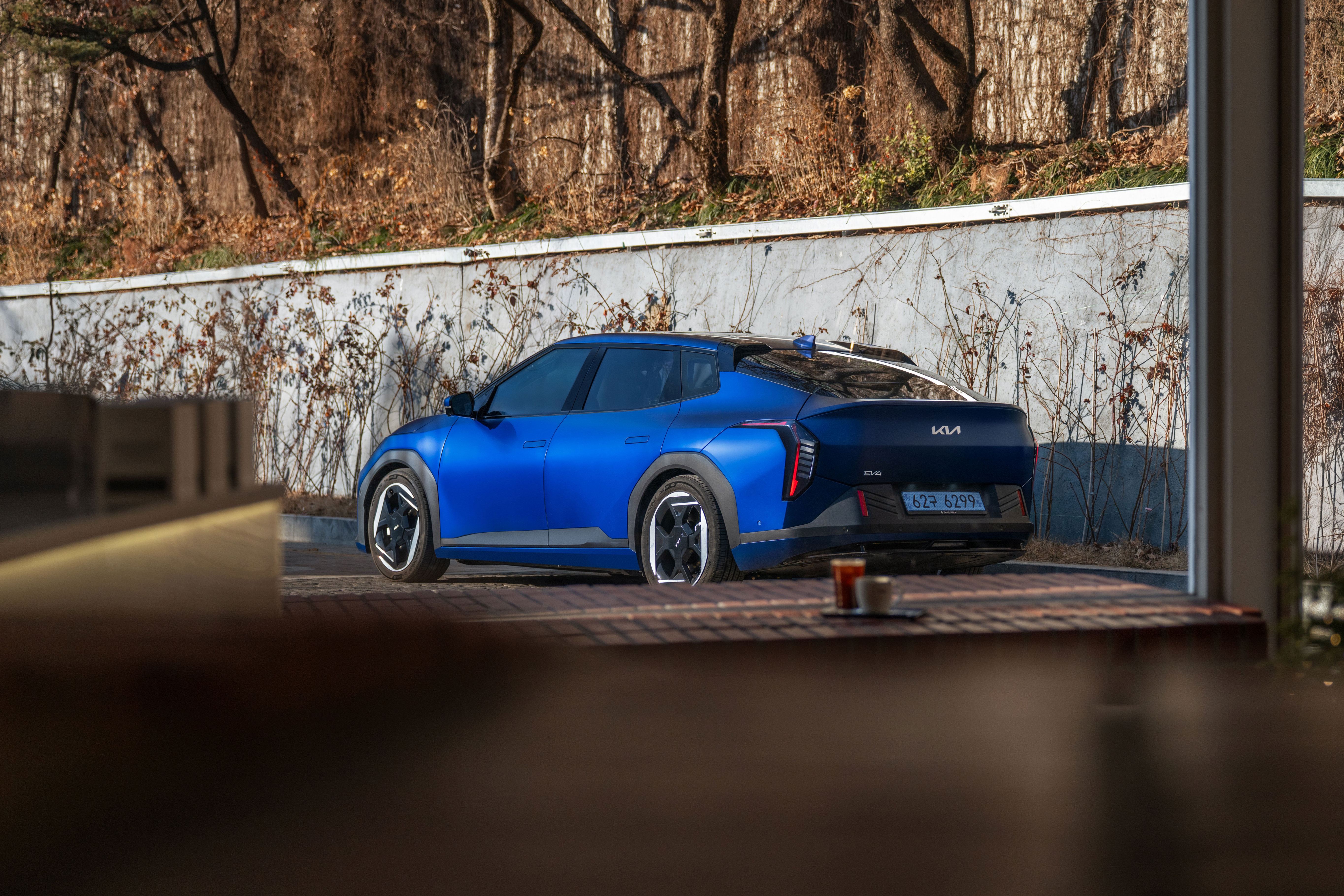 실내 창밖에서 바라본 기아 EV4 차량의 후측면