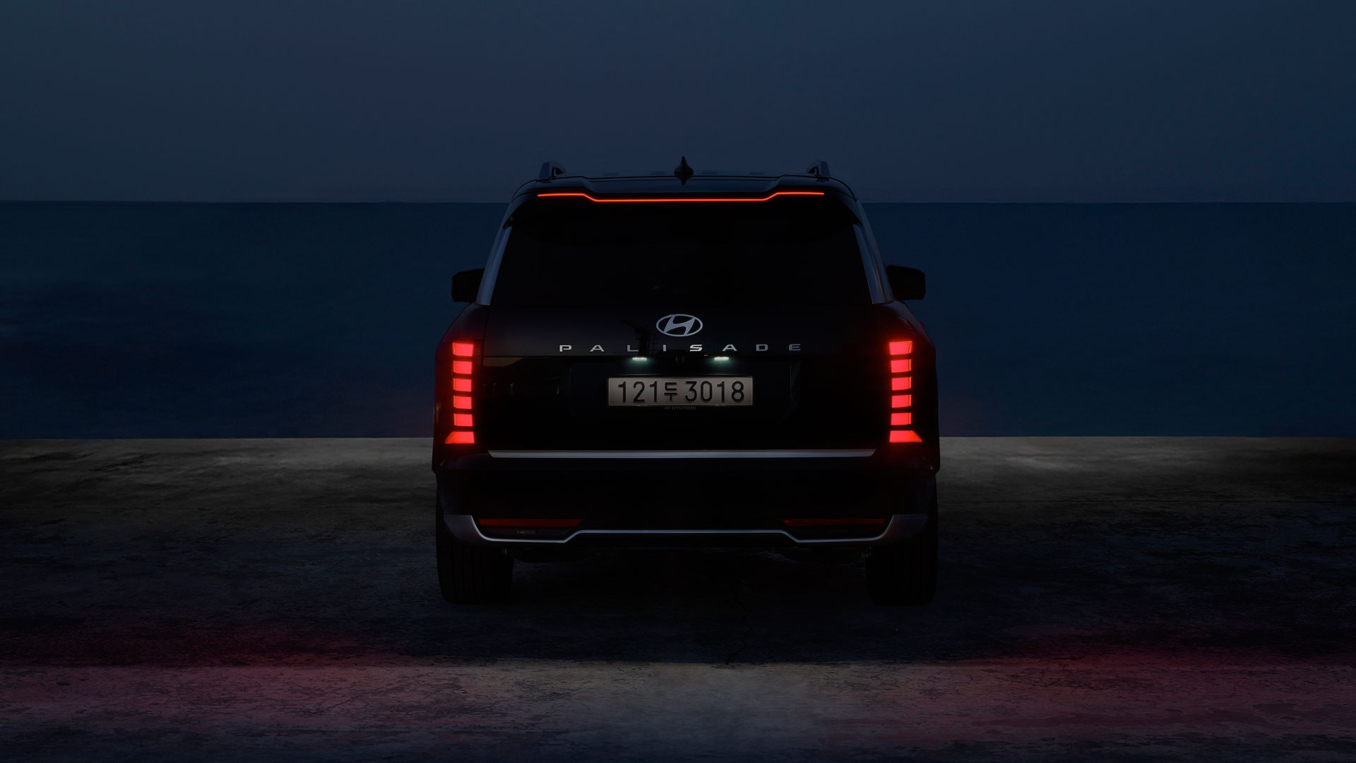야간 바다를 배경으로 현대자동차 디 올 뉴 팰리세이드 하이브리드 차량의 후면