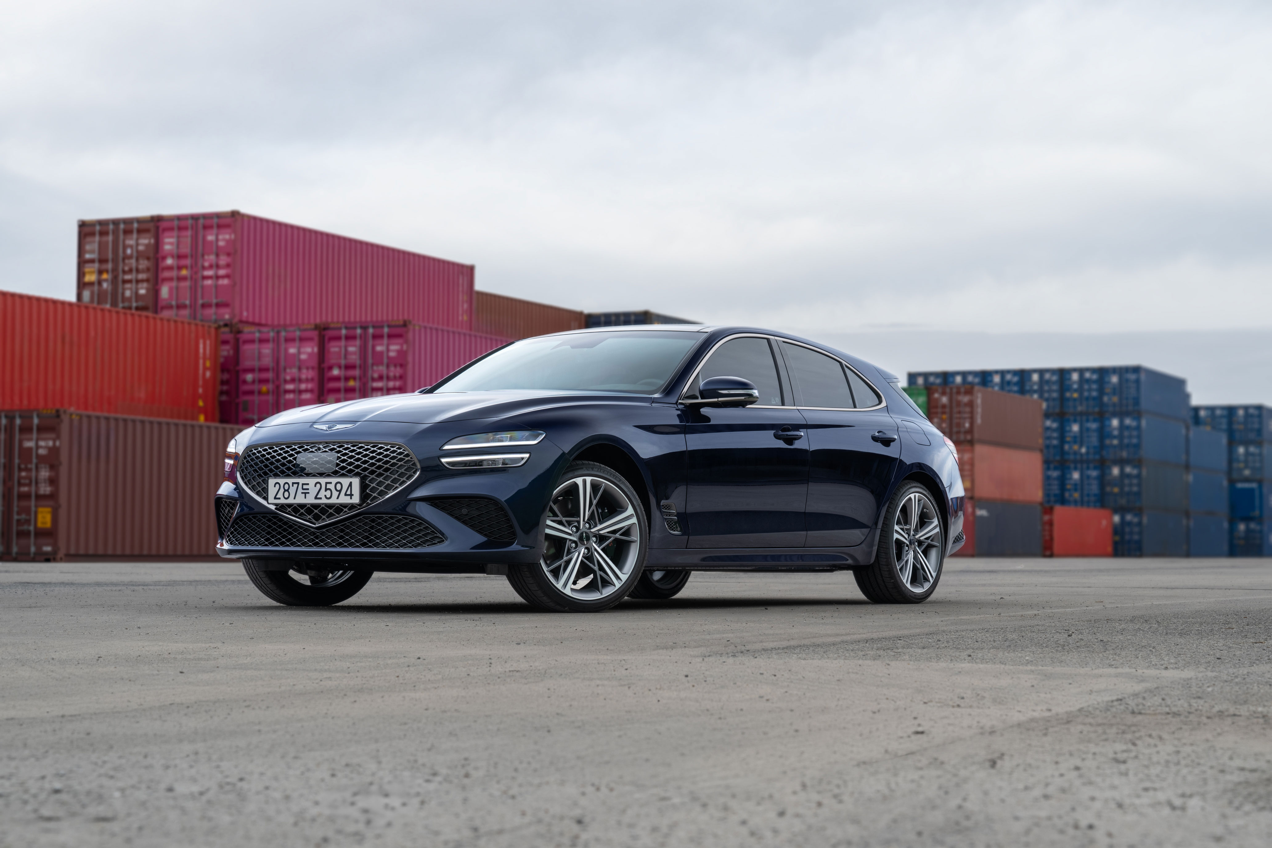 항만 컨테이너 앞에 주차된 제네시스 G70 슈팅브레이크 차량의 전측면