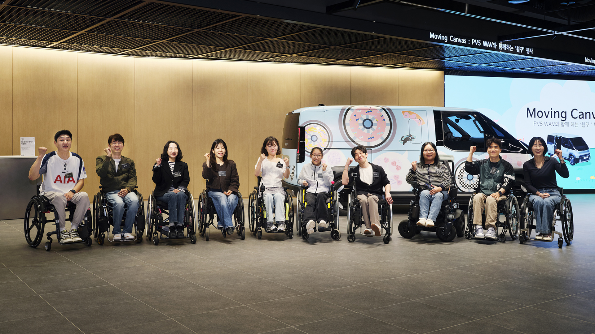 PV5 WAV 앞에 휠체어를 탄 사람들이 있는 모습