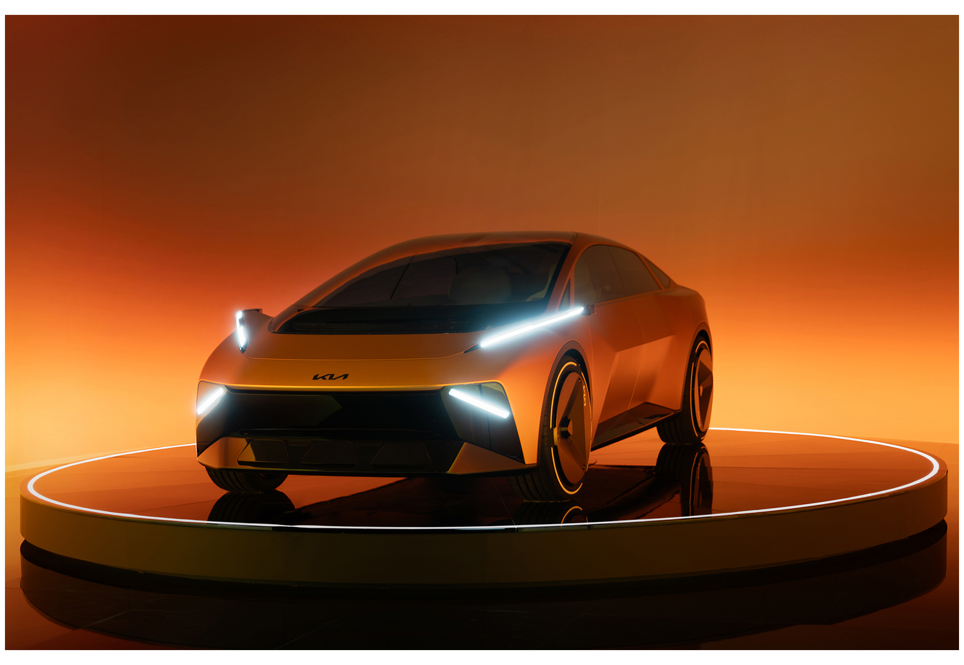 The front design of a Kia concept electric vehicle displayed on a circular stage against an orange background